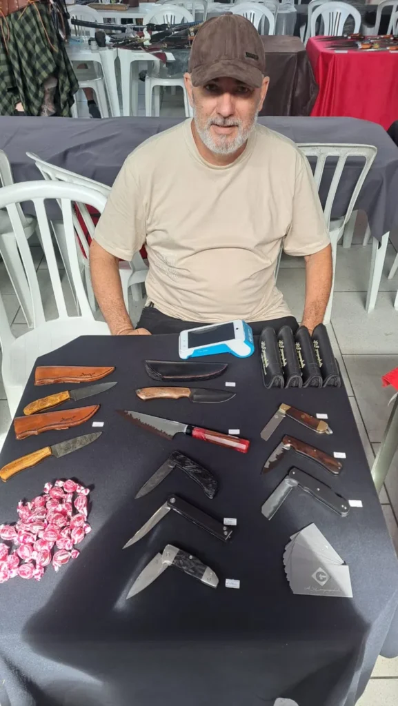 Alex Campagnholi cuteleiro artesanal brasileiro em feira de cutelaria com facas expostas
