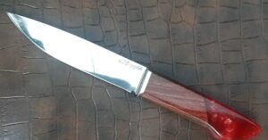 Faca de cozinha artesanal com lâmina polida em aço de lima, guarda em inox e cabo híbrido em jacarandá violeta com resina vermelha, sobre fundo em couro texturizado — Runefall Cutelaria